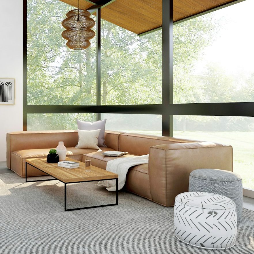 Helles Wohnzimmer mit einer beigen Couch, Kissen, einem Tisch und Pflanzen.