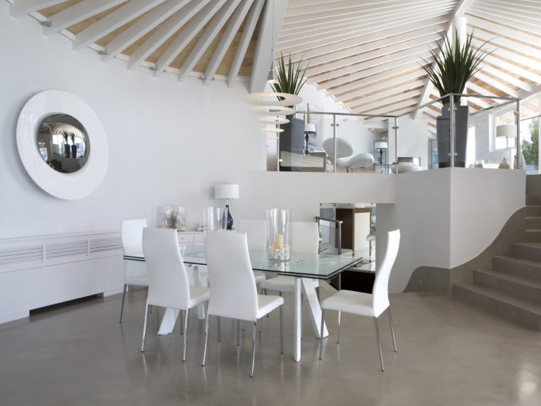 Moderne Dining-Umgebung mit Glas-Tisch, weißen Stühlen und stilvollem Holzdecke.